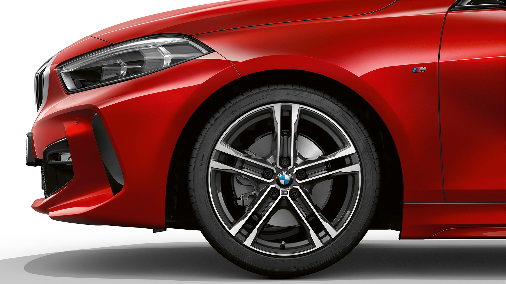 BMW serije 1 Model M Sport, bočno spreda. BMW serije 1 Model M Sport u boji Melbourne Red metaliziranoj, bočno sa 17" M aluminijumskim točkom u Double-spoke 550 M stilu u Bicolour izvedbi.