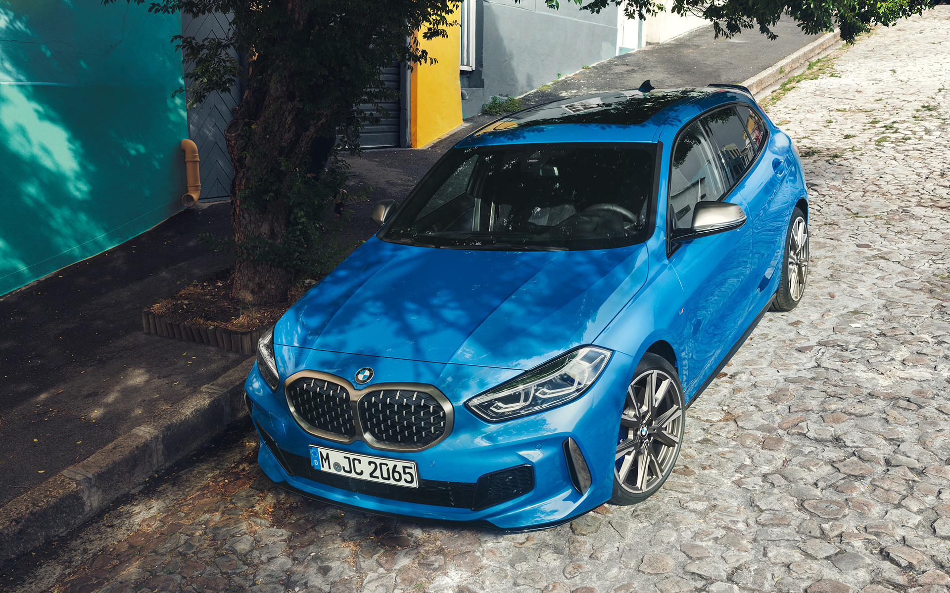 BMW Serija 1 M135i F40 pored puta BMW Serija 1 M135i F40 Misano plave metalik boje, tročetvrtinski prednji prikaz vozila parkiranog pored puta iz ptičije perspektive