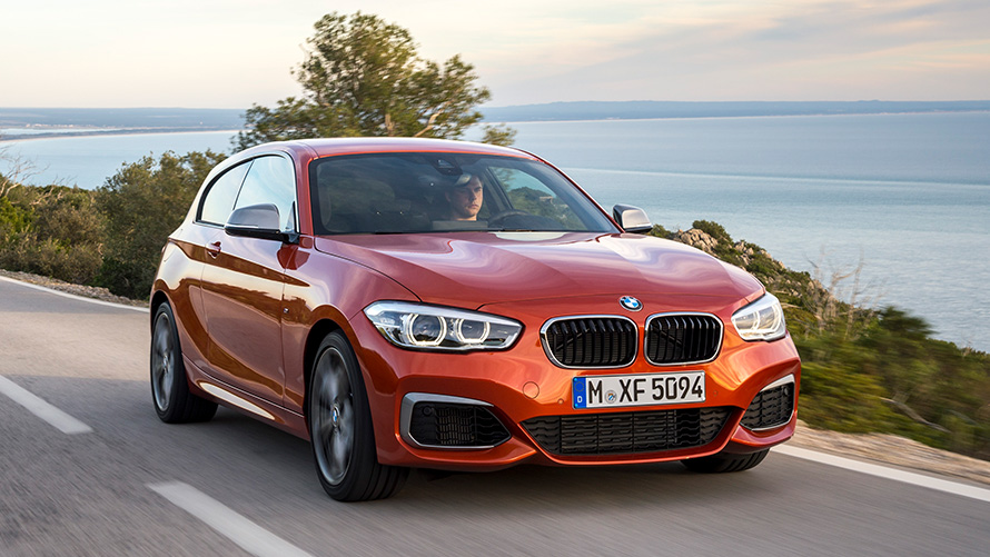 BMW M135i (F21) Tročetvrtinki prednji prikaz vozila tokom vožnje ispred jezera i planina BMW M135i (F21) Tročetvrtinki prednji prikaz vozila tokom vožnje ispred jezera i planina