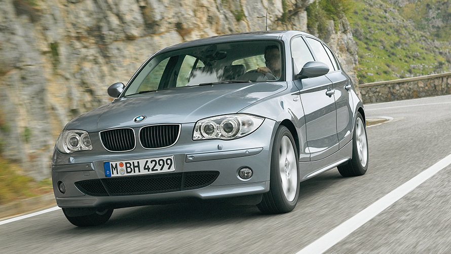 BMW Serije 1 (E87) Tročetvrtinki prednji prikaz vozila tokom vožnje ispred brda BMW Serije 1 (E87) Tročetvrtinki prednji prikaz vozila tokom vožnje ispred brda
