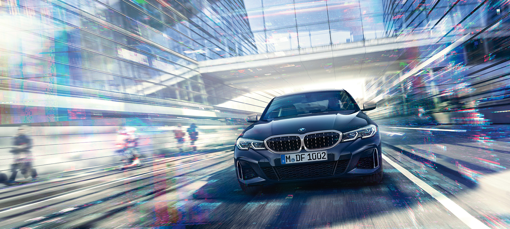 BMW Serije 3 Sedan, prednji pogled BMW M340i xDrive. Prednji pogled na BMW M340i xDrive Sedan u vožnji između urbanih staklenih zgrada.