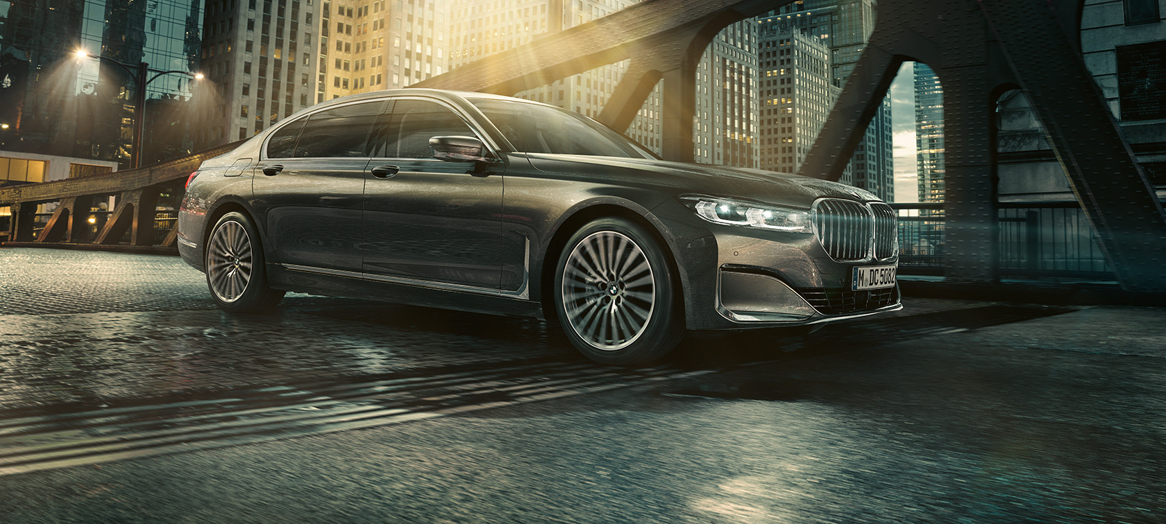 BMW Serija 7 Limuzina G11 G12 2019 bočni prikaz BMW Serija 7 Limuzina G11 G12 2019 Bernina siva sa efektom ćilibara, tročetvrtinski bočni prikaz vozila u urbanom ambijentu