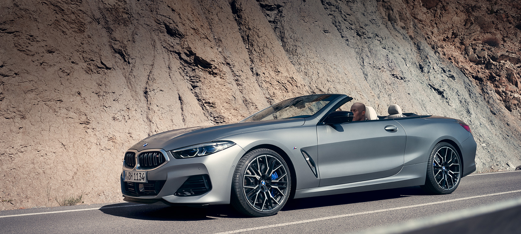 BMW Serije 8 Cabrio G14 LCI Facelift 2022 BMW M850i xDrive BMW Individual Frozen Pure sive metalik boje tročetvrtinski bočni prikaz vozila parkiranog ispred zgrade BMW Serije 8 Cabrio G14 LCI Facelift 2022 BMW M850i xDrive BMW Individual Frozen Pure sive metalik boje tročetvrtinski bočni prikaz vozila parkiranog ispred zgrade