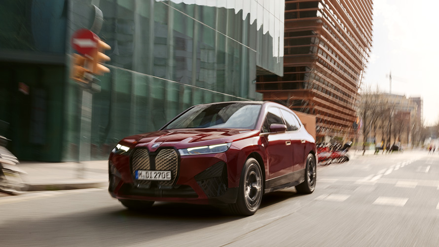 BMW iX i20 2021 električni SUV BMW iX xDrive50 Aventurin crvene boje na urbanom okruženju