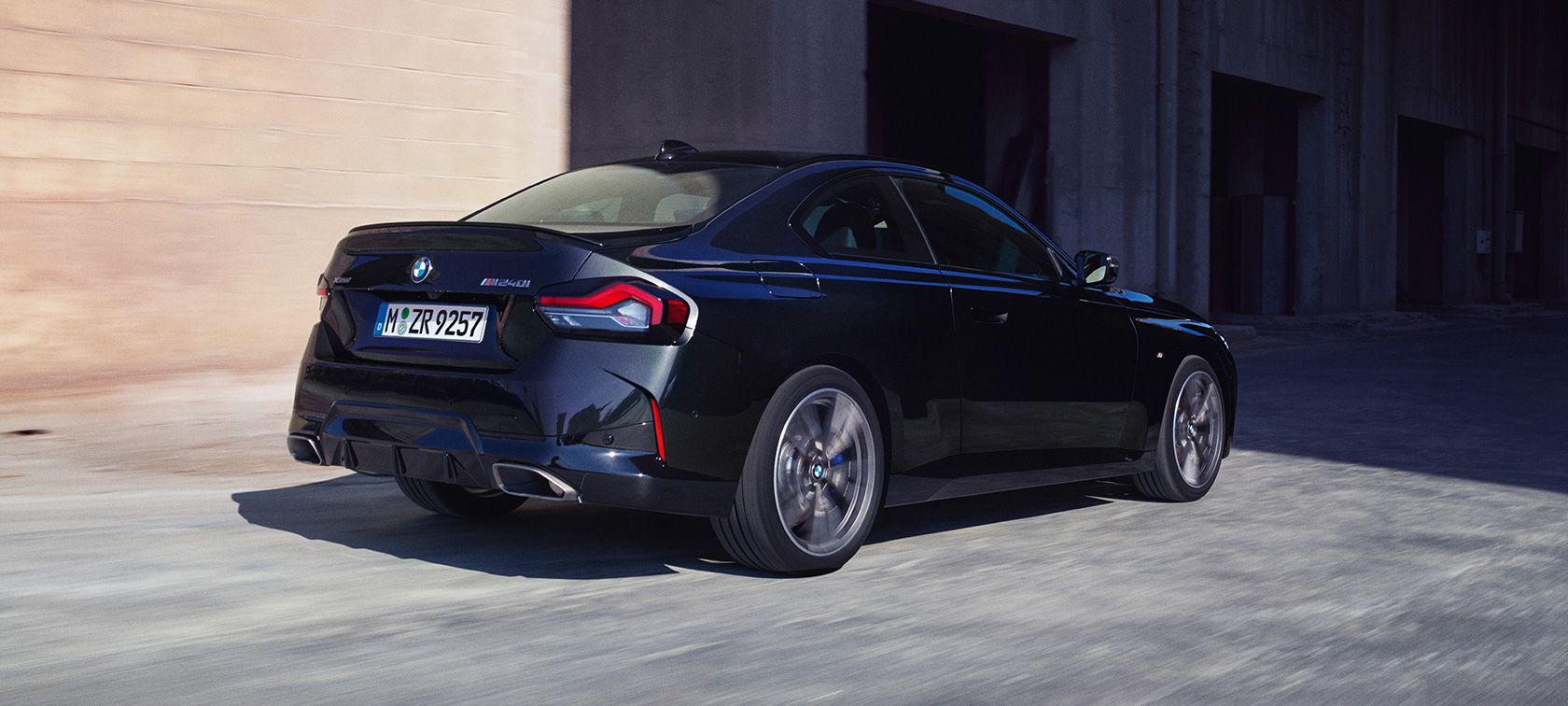 Tročetvrtinski zadnji prikaz BMW M240i xDrive Coupe G42 2021 BMW M240i xDrive Coupe G42 2021 Black Sapphire metalik boja tročetvrtinski zadnji prikaz vozila u pokretu