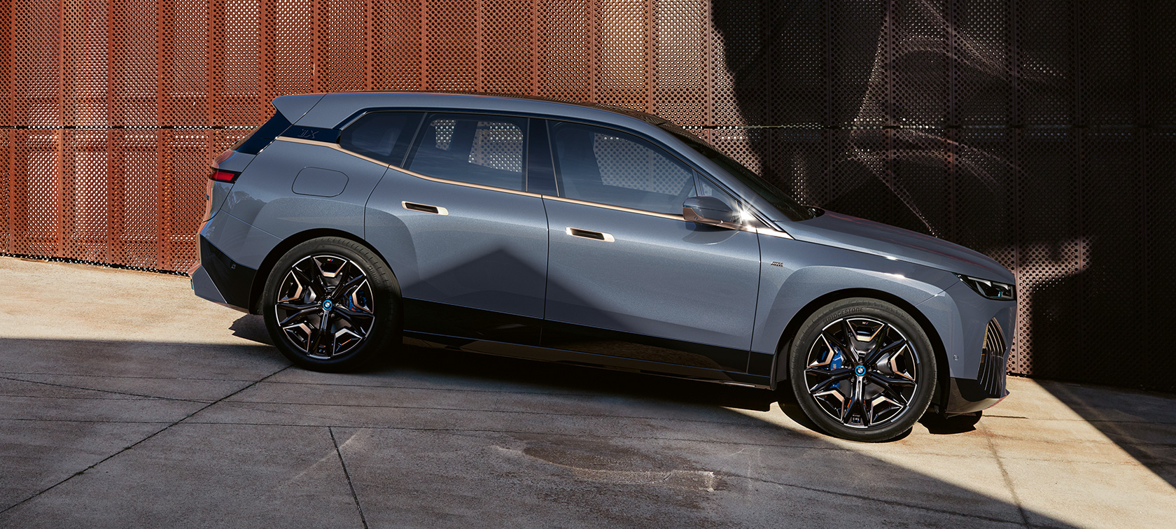 BMW iX M60 i20 2022 električni SUV Oxid sive metalik boje bočni prikaz parkiranog vozila BMW iX M60 i20 2022 električni SUV Oxid sive metalik boje bočni prikaz parkiranog vozila