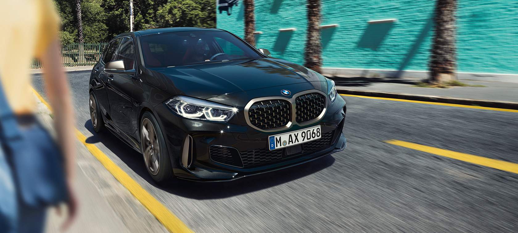 BMW M135i (F40), tročetvrtinski prednji prikaz BMW M135i xDrive (F40) u Black Sapphire metalik boji, tročetvrtinski prednji prikaz vozila u pokretu