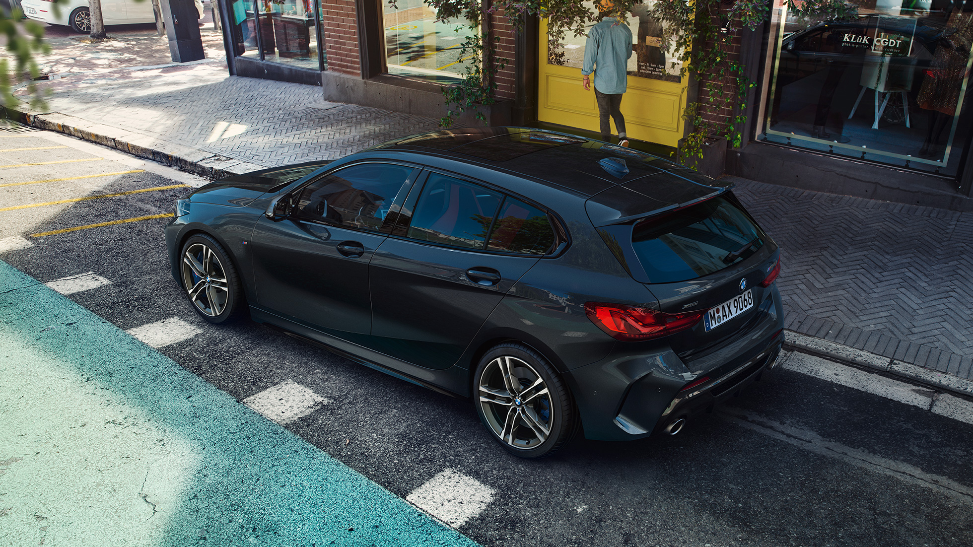 BMW M135i xDrive, u parkiranju. BMW M135i xDrive u boji Black Sapphire metaliziranoj u parkiranju, pogfled sa strane iz ptičje perspektive.