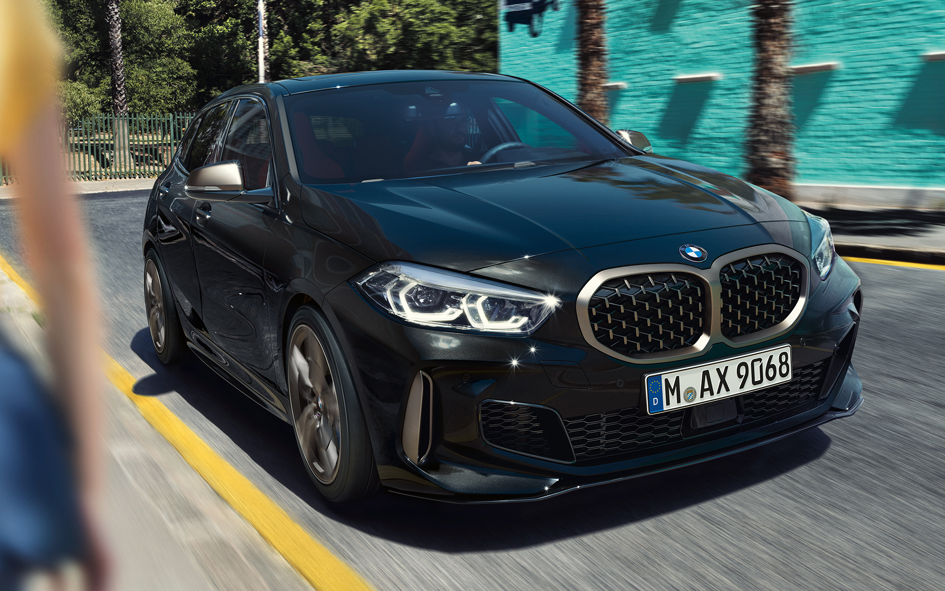 BMW M135i xDrive (F40) u Black Sapphire metalik boji tročetvrtinski prednji prikaz vozila u pokretu