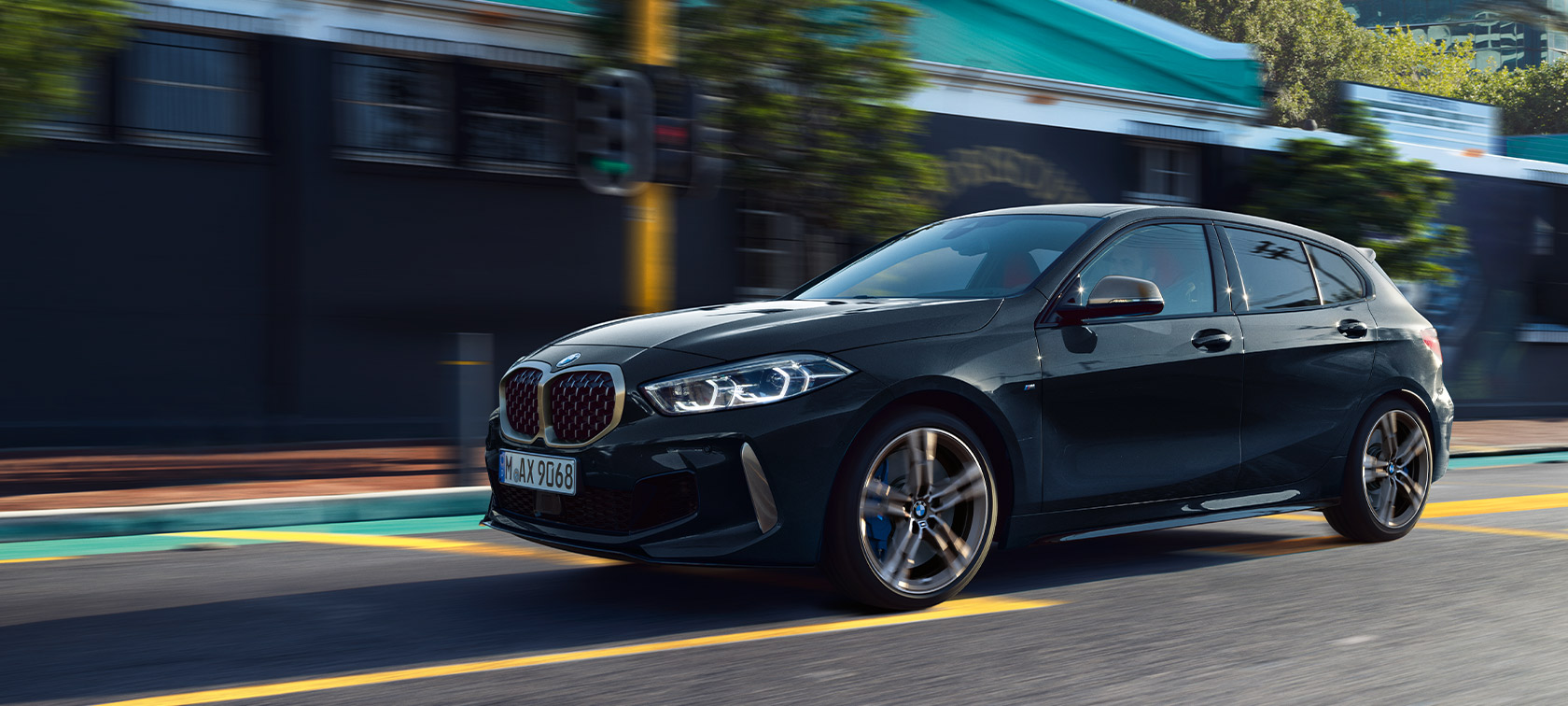 BMW M135i xDrive ( F40 ) Black Sappire metalik boja, vozilo u pokretu kroz urbano okruženje