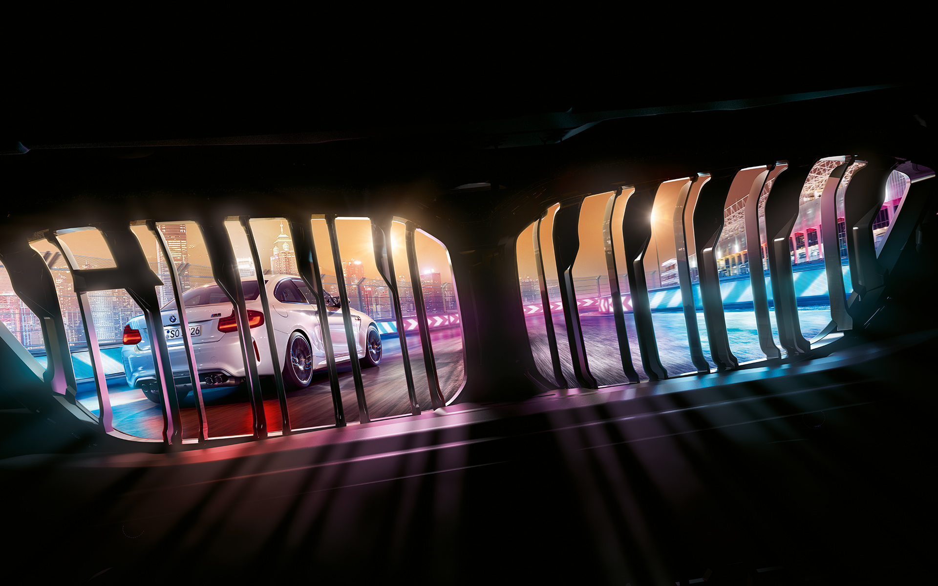 BMW M2 Competition rešetka Pogled kroz BMW prednju rešetku na model BMW M2 Competition koji odmiče na noćnoj trkačkoj stazi.