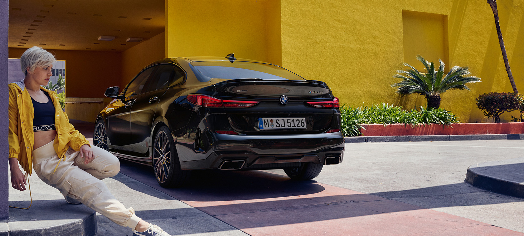 BMW M235i xDrive Gran Coupé tročetvrtinski pogled BMW M235i xDrive Gran Coupé boja Black Sapphire metalizirana F44 tročetvrtinski pogled otpozadi sa ženom napred