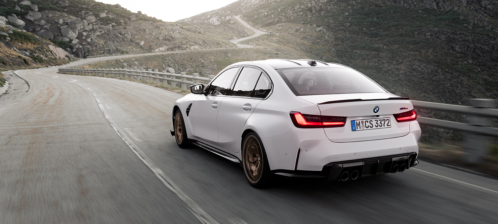 BMW M3 CS G80 tročetvrtinski zadnji prikaz vozila tokom vožnje BMW M3 CS G80 tročetvrtinski zadnji prikaz vozila tokom vožnje planinskim putem