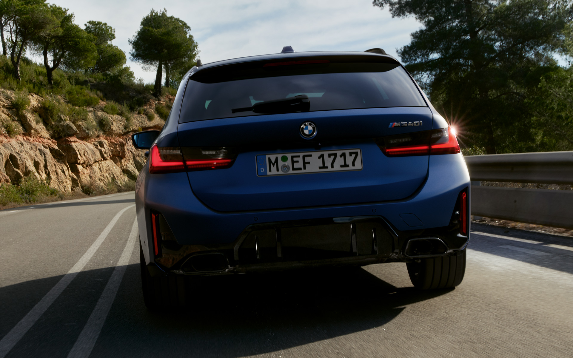 BMW M340i xDrive Touring G21 zadnji prikaz vozila tokom vožnje ulicom BMW M340i xDrive Touring G21 Frozen Tanzanite plave boje zadnji prikaz vozila tokom vožnje ulicom