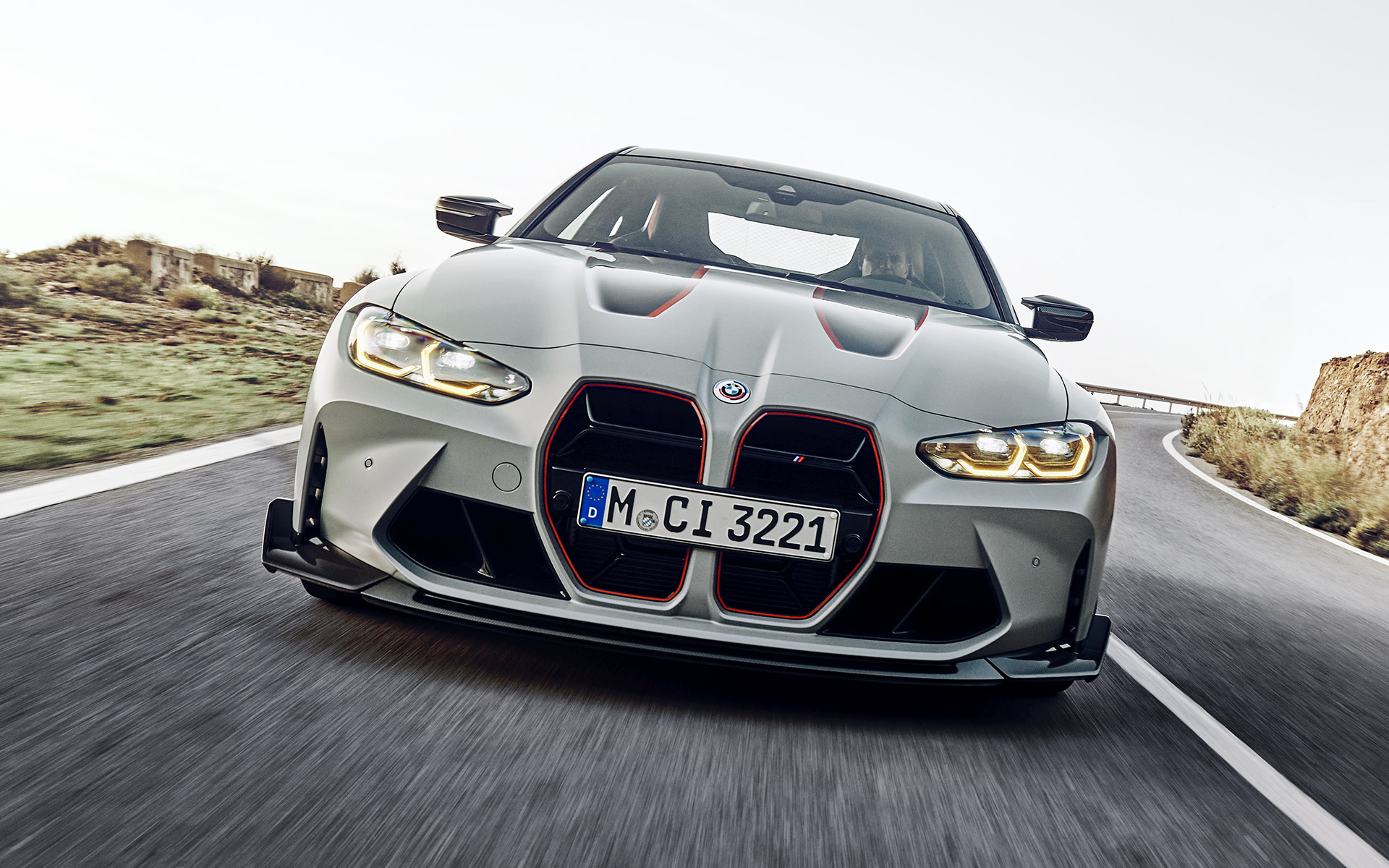 Letvice prednje maske u crnoj boji sa prepoznatljivim omotom od folije crvene boje BMW M4 CSL G82 BMW M4 CSL G82 BMW Individual Frozen Brooklyn sive metalik boje Letvice prednje maske crne boje sa prepoznatljivim omotačem od folije u crvenom boji prednji prikaz vozila tokom vožnje ulicom