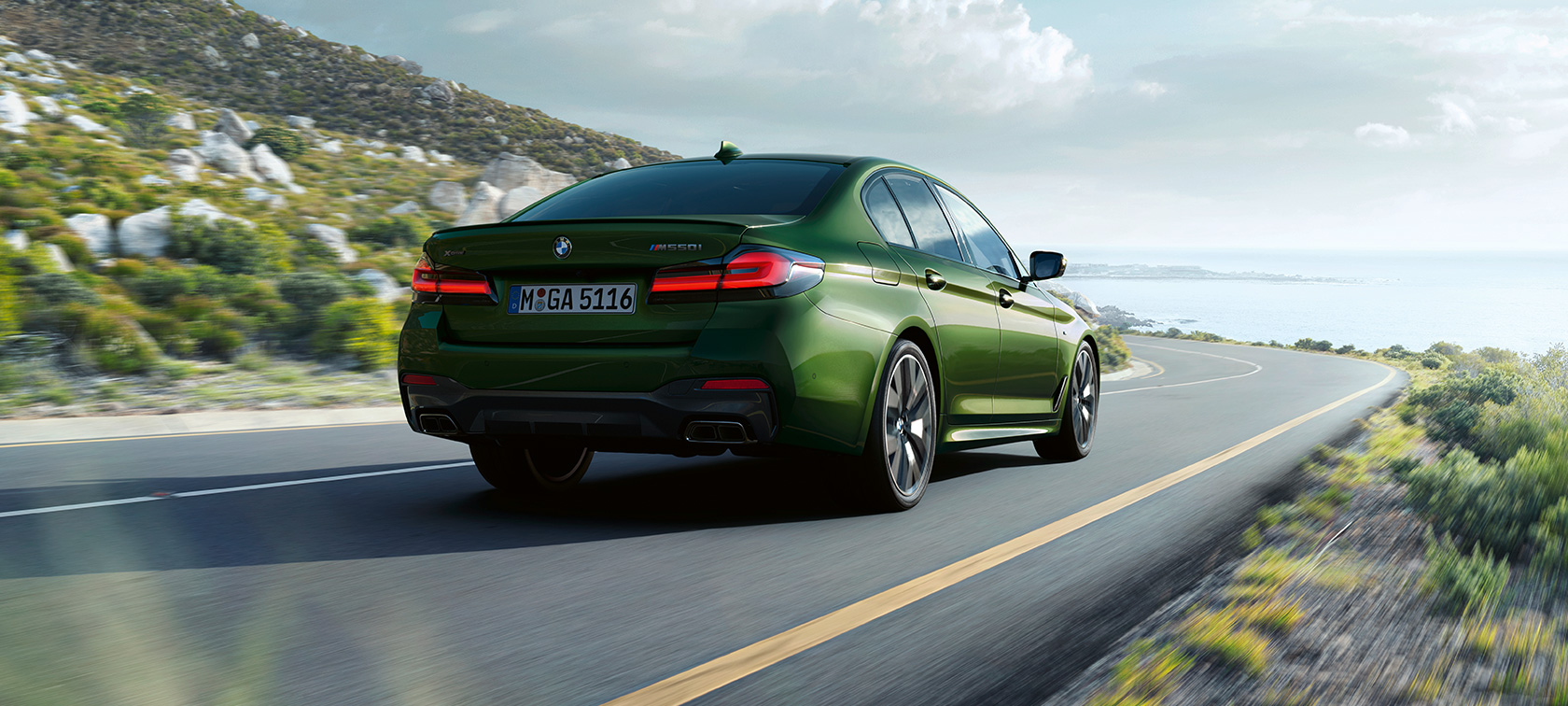BMW M550i xDrive Limuzina G30 LCI Facelift 2020 tročetvrtinski stražnji prikaz u vožnji BMW M550i xDrive Limuzina G30 LCI Facelift 2020 BMW Individual Verde Ermes metalik tročetvrtinski stražnji prikaz u vožnji