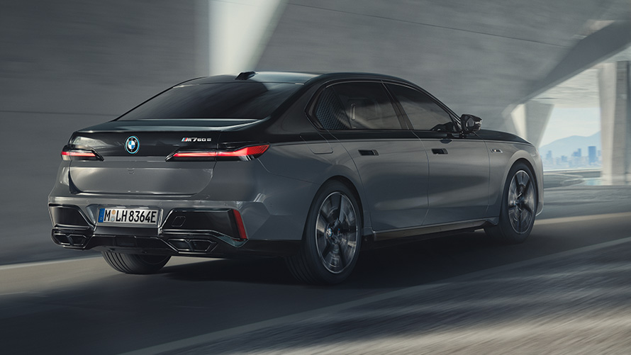 BMW M760e xDrive Sedan G70 M Performance paket BMW M760e xDrive Sedan G70 M Performance paket BMW Individual dvonijansna Black Sapphire metalik boja karoserije BMW Individual Dravite siva metalik boja tročetvrtinski zadnji prikaz vozila tokom vožnje ulicom