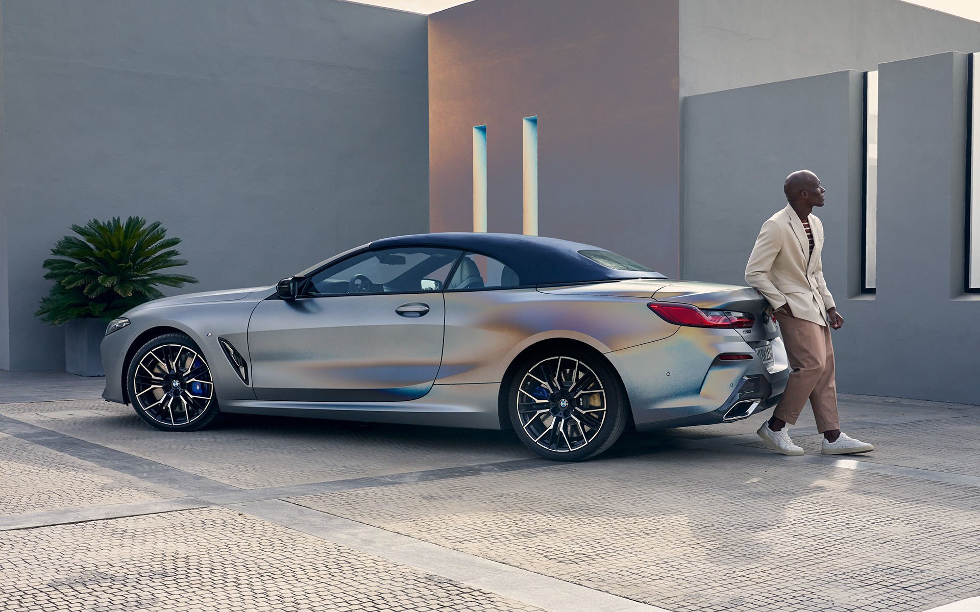 Tročetvrtinski zadnji prikaz BMW M850i xDrive Kabriolet G14 LCI Facelift 2022 BMW M850i xDrive Kabriolet G14 LCI Facelift 2022 BMW Individual Frozen Pure siva metalik boja tročetvrtinski zadnji prikaz s modelom naslonjenim na vozilu
