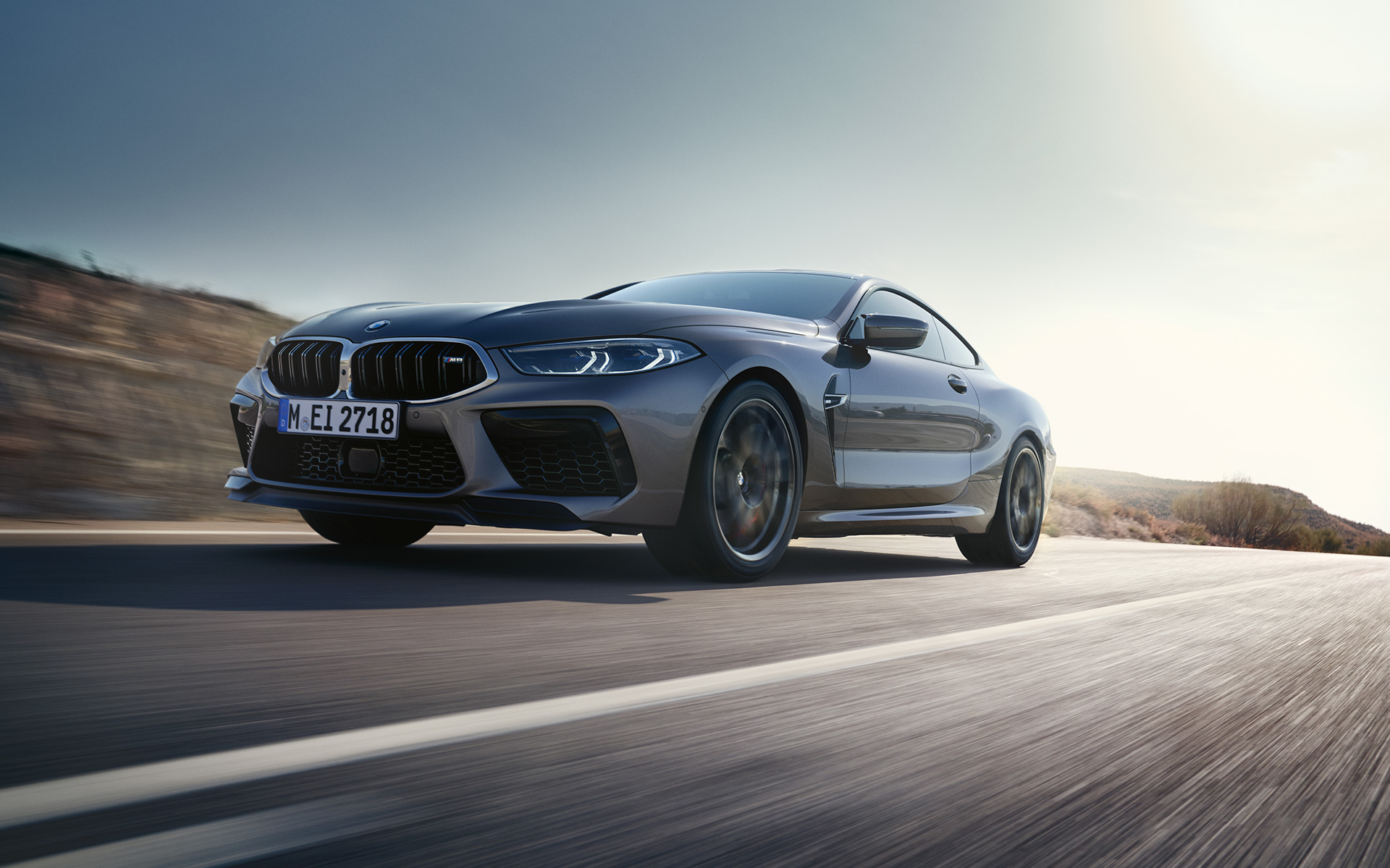Tročetvrtinski prednji prikaz BMW M8 Coupé F92 LCI Facelift 2022 tokom vožnje autoputem BMW M8 Coupé F92 LCI Facelift 2022 Skyscraper sive metalik boje tročetvrtinski prednji prikaz vozila tokom vožnje autoputem iz niskog ugla