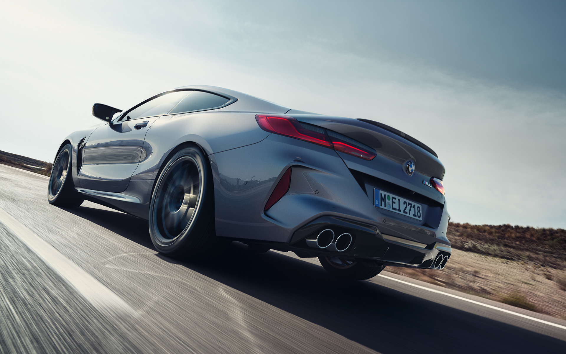 Tročetvrtinski zadnji prikaz BMW M8 Coupé F92 LCI Facelift 2022 tokom vožnje autoputem BMW M8 Coupé F92 LCI Facelift 2022 Skyscraper sive metalik boje tročetvrtinski zadnji prikaz vozila tokom vožnje autoputem iz niskog ugla