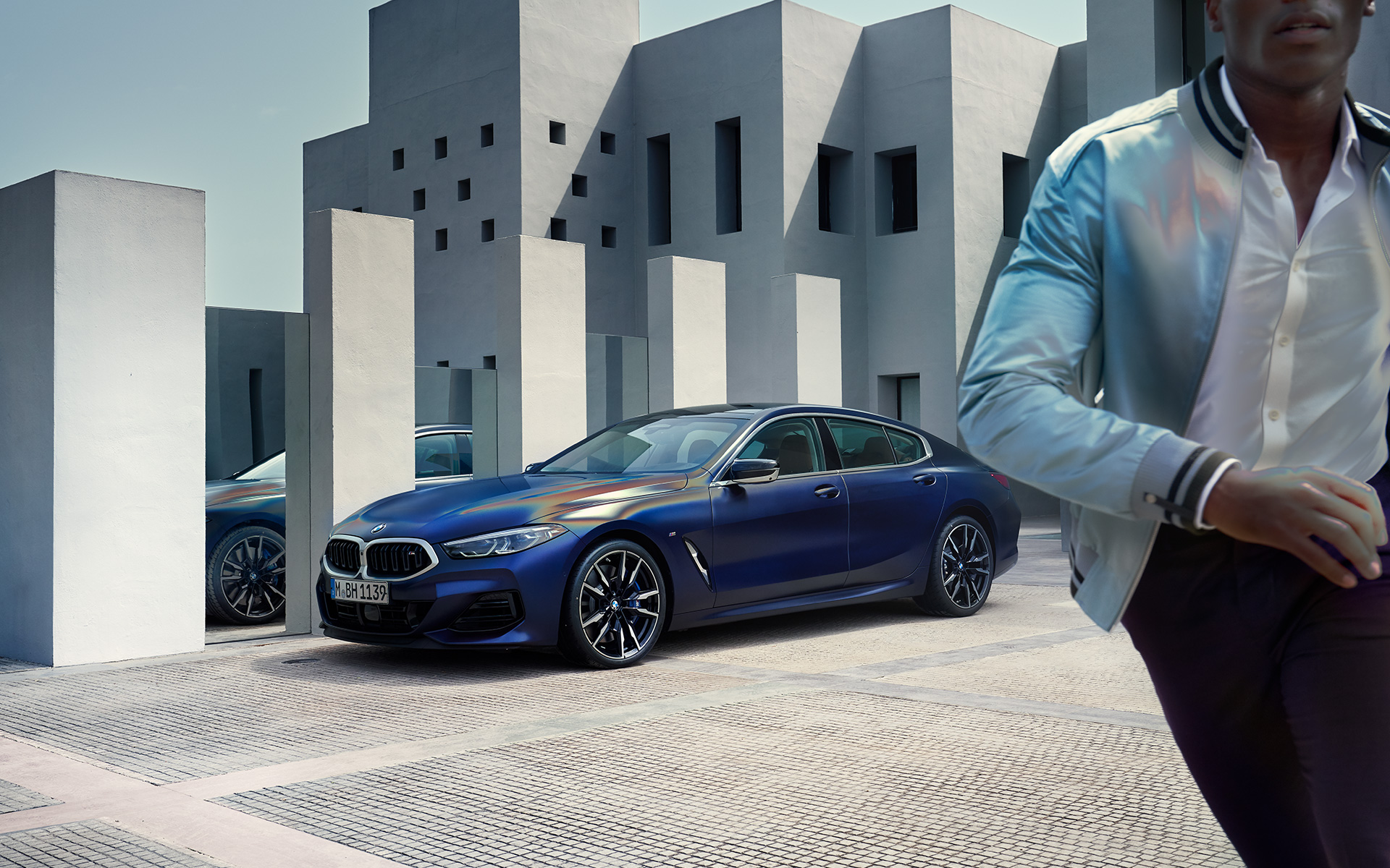 Tročetvrtinski prednji prikaz BMW M850i Gran kupe G16 LCI Facelift 2022 BMW M850i xDrive Gran kupe G16 LCI Facelift 2022 BMW Individual Frozen Tanzanite plava metalik boja tročetvrtinski prednji prikaz vozila sa muškim modelom u prvom planu
