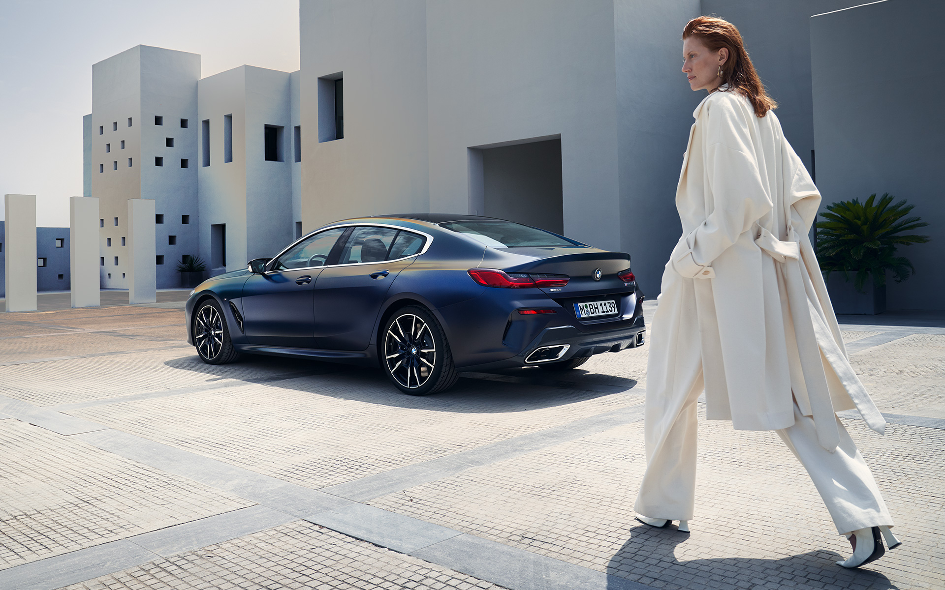 BMW M850i xDrive Gran kupe G16 LCI Facelift 2022 bočni prikaz s ženskim modelom BMW M850i xDrive Gran kupe G16 LCI Facelift 2022 BMW Individual Frozen Tanzanite plava metalik tročetvrtinski zadnji prikaz vozila sa ženskim modelom