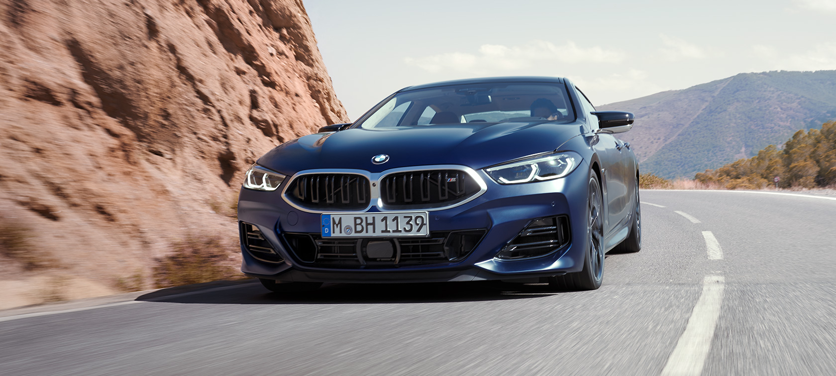 Tročetvrtinski prednji prikaz vozila tokom vožnje BMW M850i Gran kupe G16 LCI Facelift 2022 BMW M850i xDrive Gran kupe G16 LCI Facelift 2022 BMW Individual Frozen Tanzanite plava metalik boja Tročetvrtinski prednji prikaz vozila prilikom ulaska u krivinu