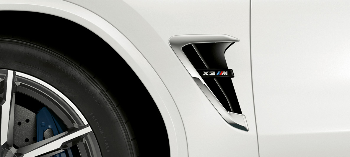 BMW X3 M, M prorez. BMW X3 M u boji Alpine White, eksterijer, M prorez sa hromiranim detaljima i oznakom modela.
