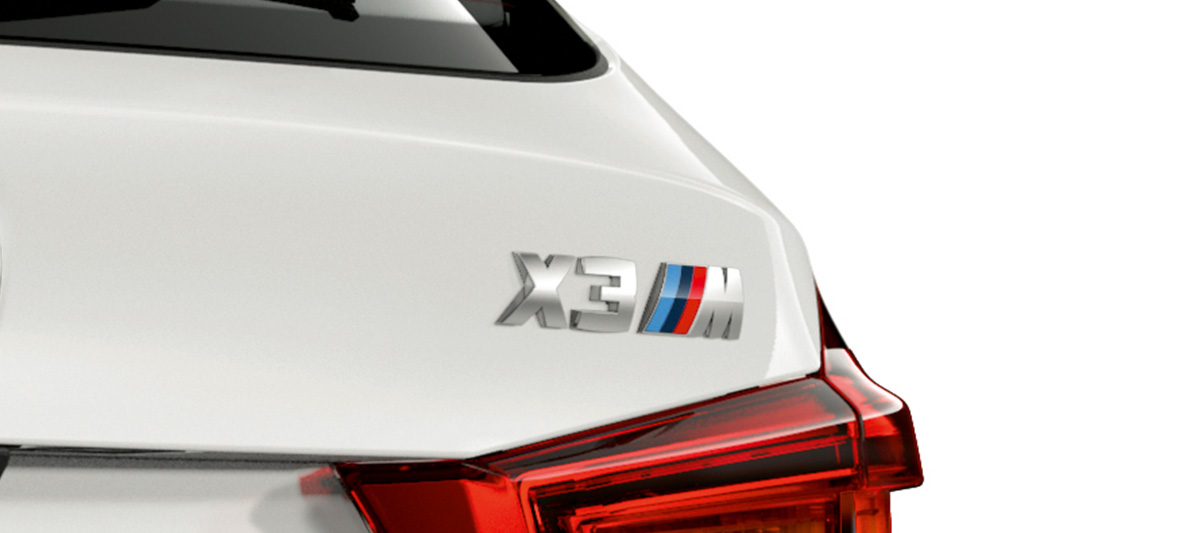BMW X3 M, oznaka modela. BMW X3 M u boji Alpine White, eksterijer, otpozadi sa oznakom modela.