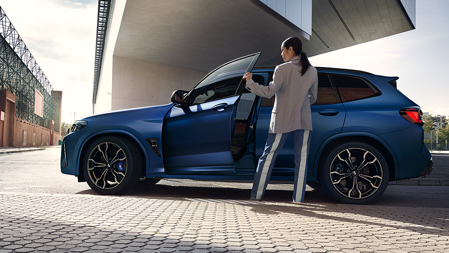 BMW X3 M Competition F97 LCI Facelift 2021, bočni prikaz s otvorenim vratima i modelom BMW X3 M Competition F97 LCI Facelift 2021 Frozen Marina Bay plave metalik boje, bočni prikaz s otvorenim vratima i modelom