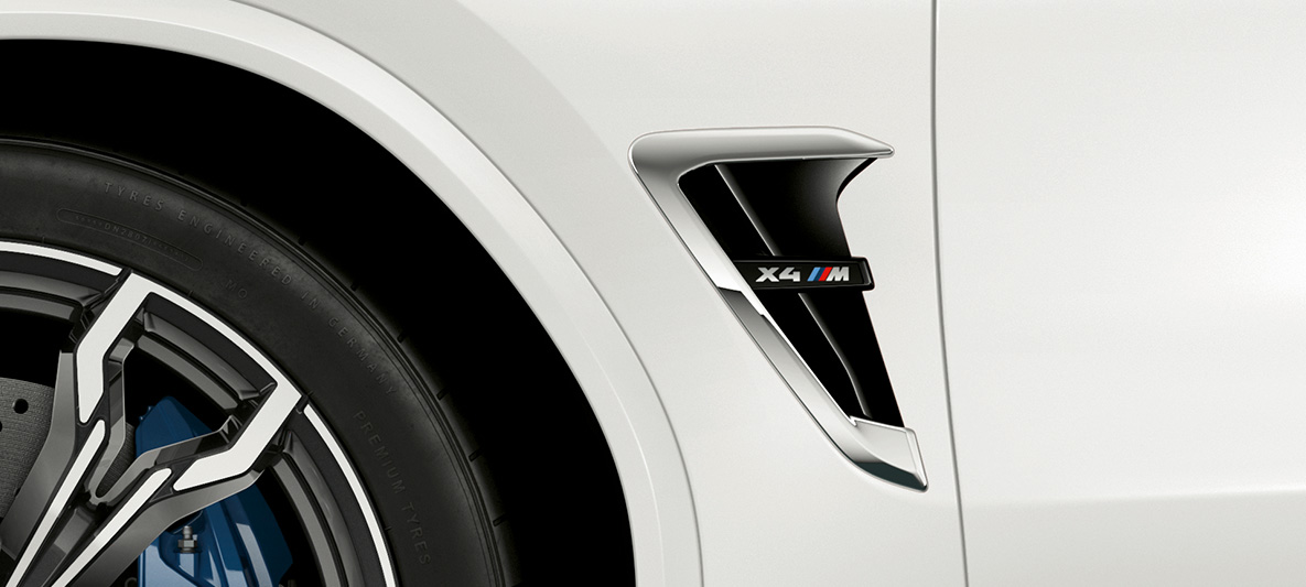 BMW X4 M, M prorez. BMW X4 M u boji Alpine White, eksterijer, M prorez sa hromiranim detaljima i oznakom modela.