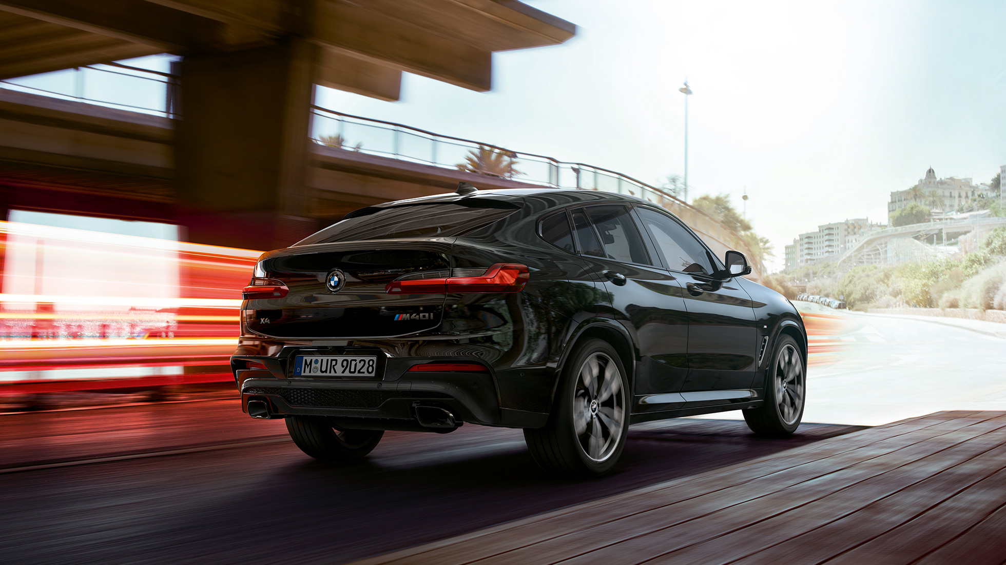 BMW X4 M40i in, tročetvrtinski pogled spreda. BMW X4 M40i u boji Black Sapphire metaliziranoj, u vožnji, eksterjer, ročetvrtinski pogled spreda sa svetlonsim prugama.