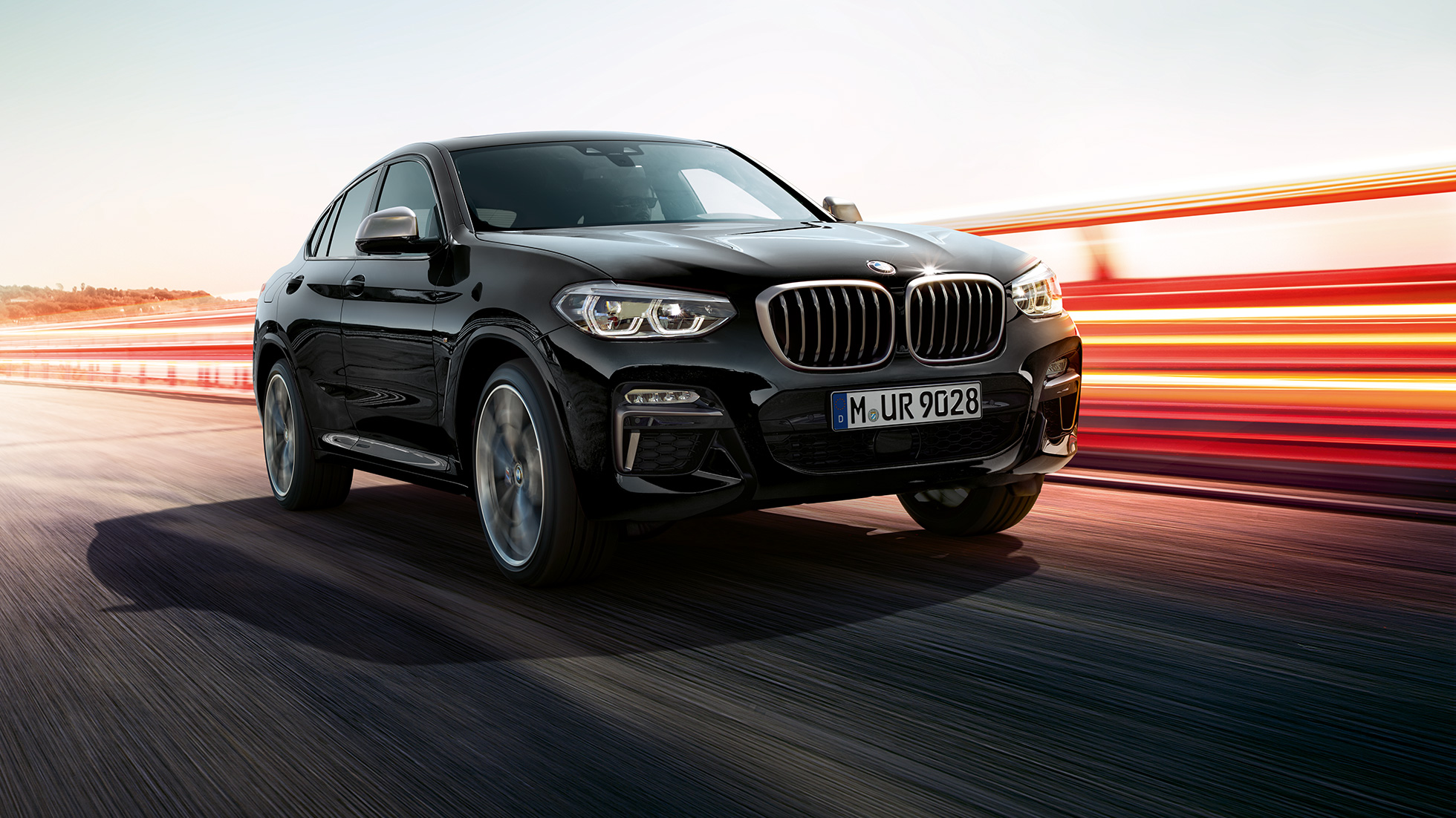 BMW X4 M40i i BMW X4 M40d, tročetvrtinski pogled spreda. BMW X4 M40i i BMW X4 M40d u boji Black Sapphire metaliziranoj, eksterijer, tročetvrtinski pogled spreda, leva strana sa svetlosnim prugama.