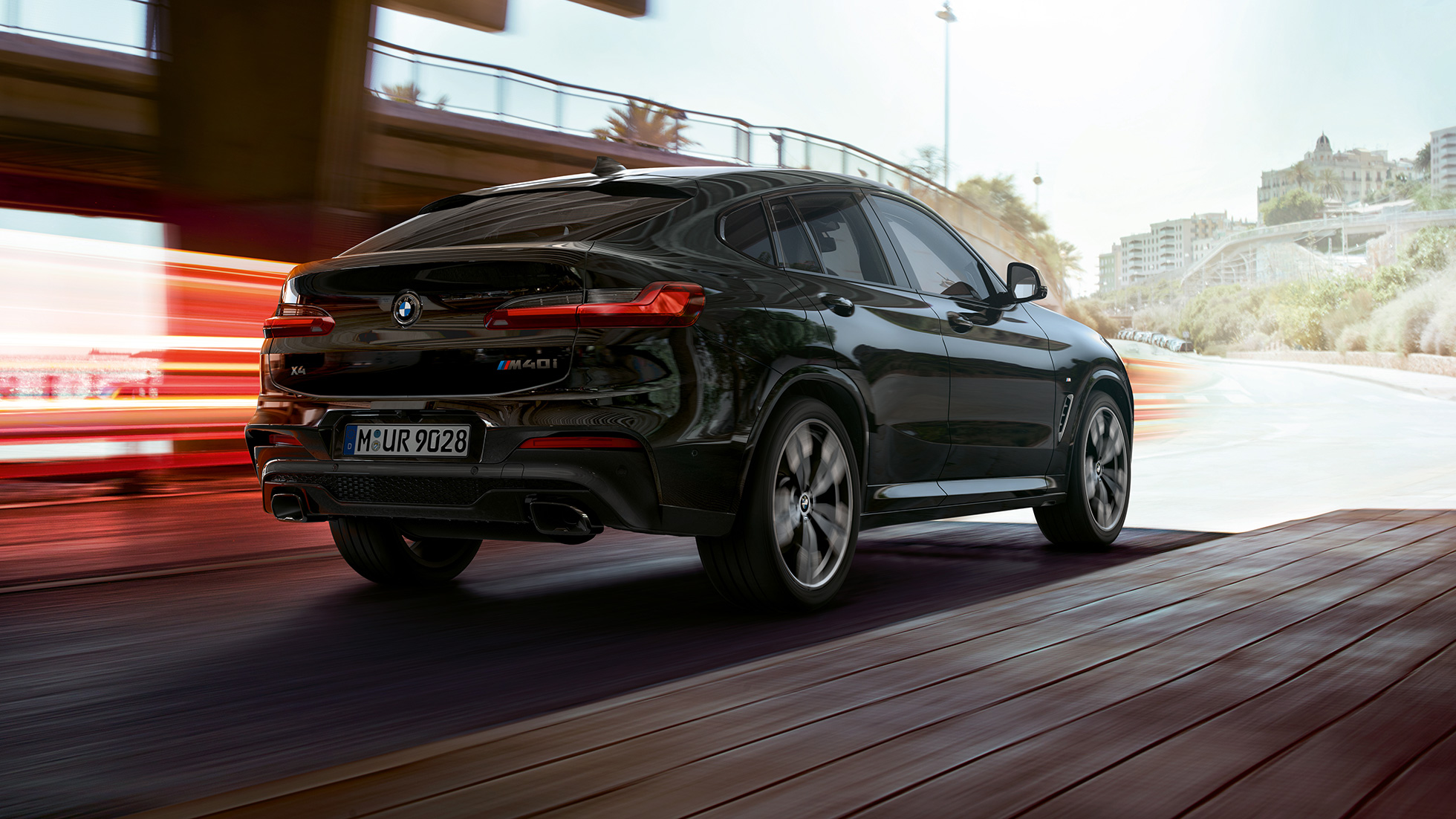 BMW X4 M40i, tročetvrtinski pogled otpozadi. BMW X4 M40i u boji Black Sapphire metaliziranoj, eksterijer, tročetvrtinski pogled otpozadi, desta strana sa svetlosnim prugama.