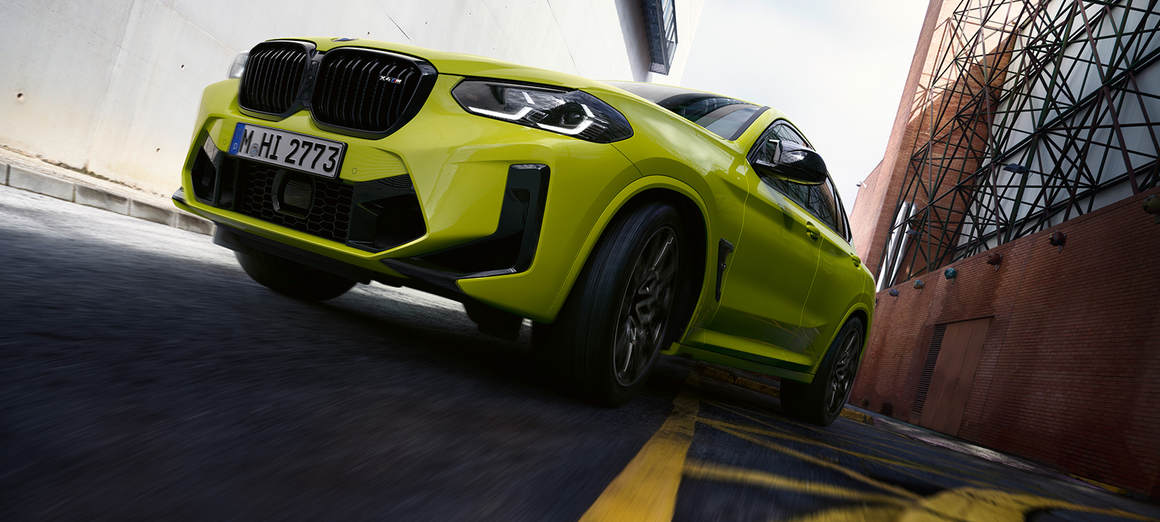 Tročetvrtinski prednji prikaz odozdo BMW-a X4 M Competition F98 LCI 2021 BMW X4 M Competition F98 LCI Facelift 2021 Sao Paulo žute boje tročetvrtinski prednji prikaz vozila odozdo prilikom vožnje između zgrada