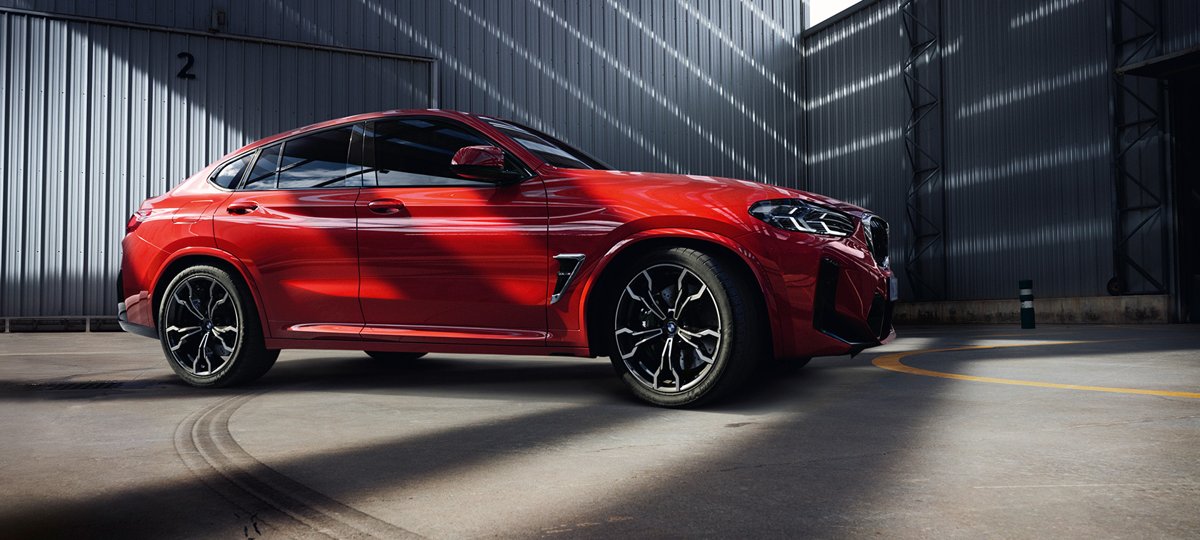 Tročetvrtinski prednji prikaz BMW-a X4 M F98 LCI Facelift 2021 BMW X4 M Competition F98 LCI Facelift 2021 Toronto crvene metalik boje tročetvrtinski prednji prikaz u zgradi fabrike