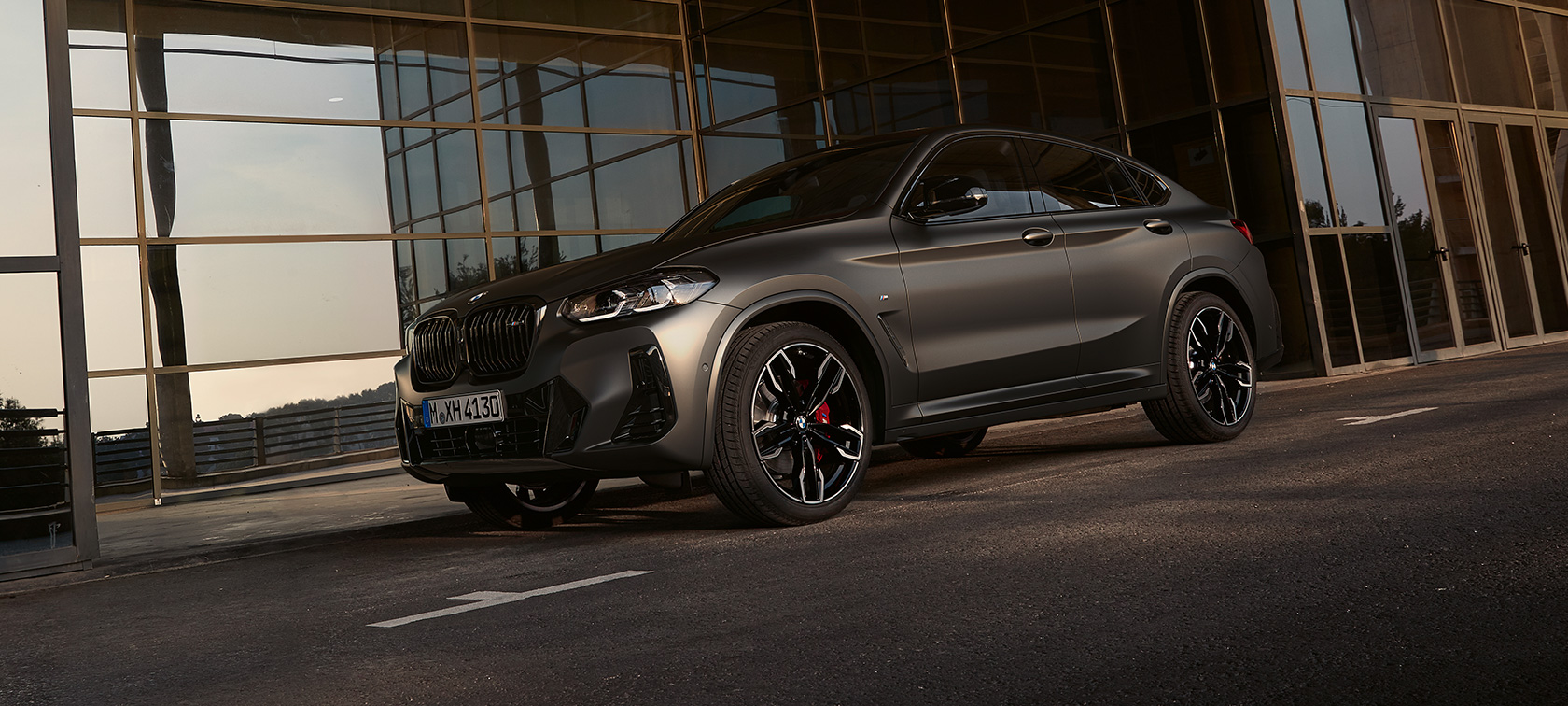 Tročetvrtinski prednji prikaz BMW-a X4 M40i G02 LCI 2021 Facelift BMW X4 M40i G02 LCI Facelift tročetvrtinski prednji prikaz ispred staklene fasade