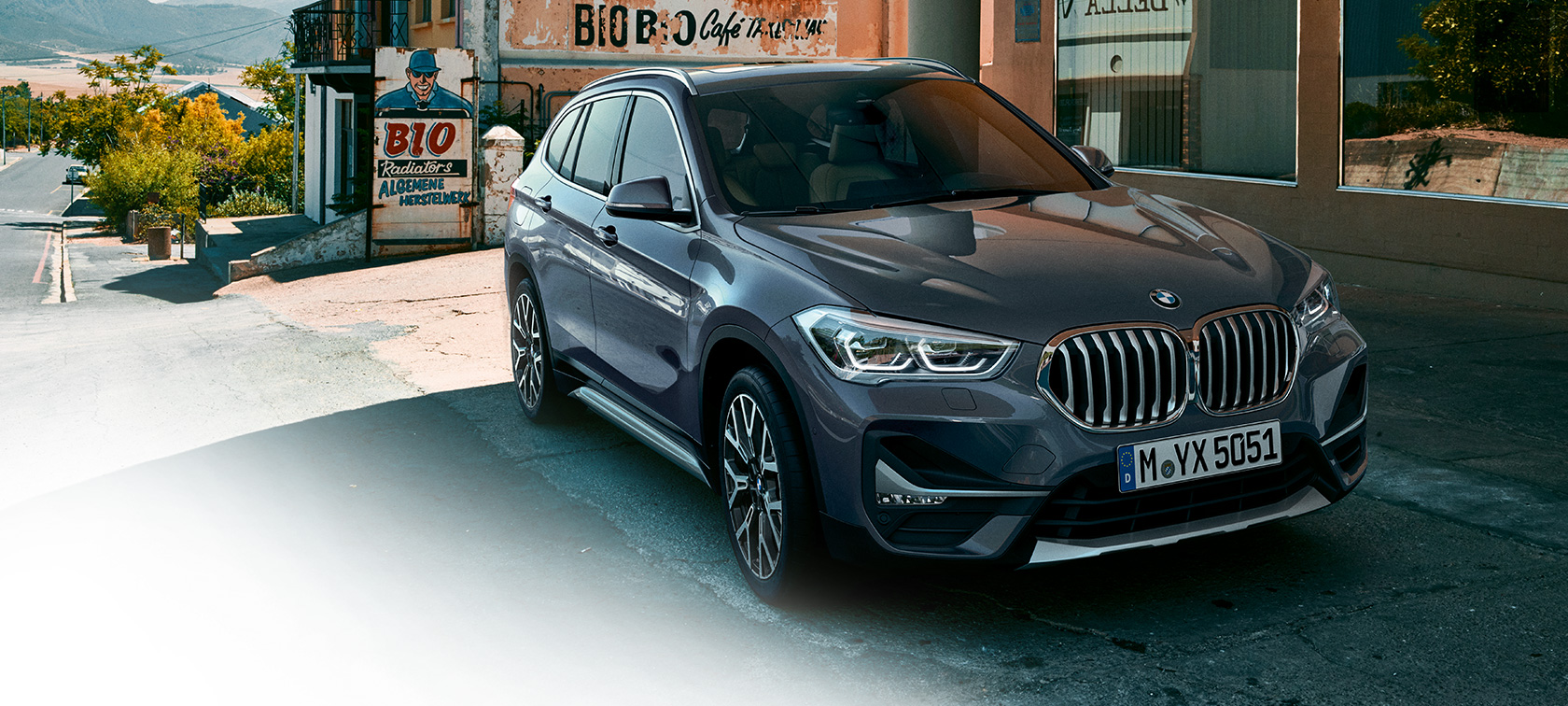 BMW X1, tročetvrtinski pogled spreda BMW X1, tročetvrtinski pogled spreda dok stoji ispred urbanog pejzaža