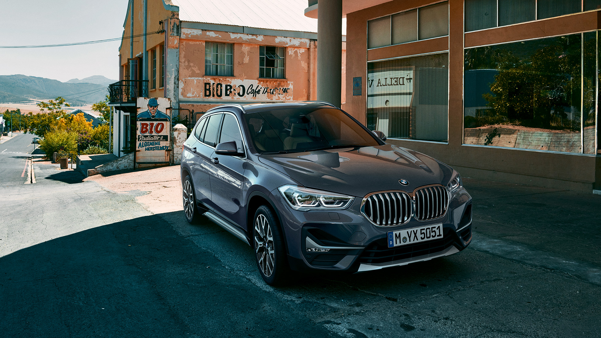 BMW X1, tročetvrtinski pogled spreda. BMX X1, tročetvrtinski pogled spreda dok stoji ispred urbanog pejzaža.
