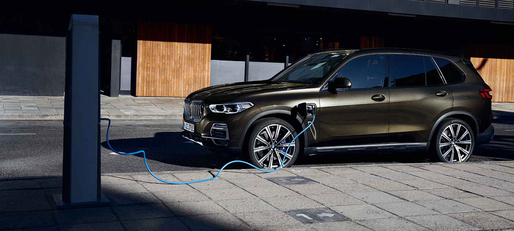 Plug-in hibrid BMW X5 xDrive45e G05 tročetvrtinski bočni prikaz Plug-in hibrid BMW X5 xDrive45e G05 tročetvrtinski bočni prikaz vozila prilikom punjenja