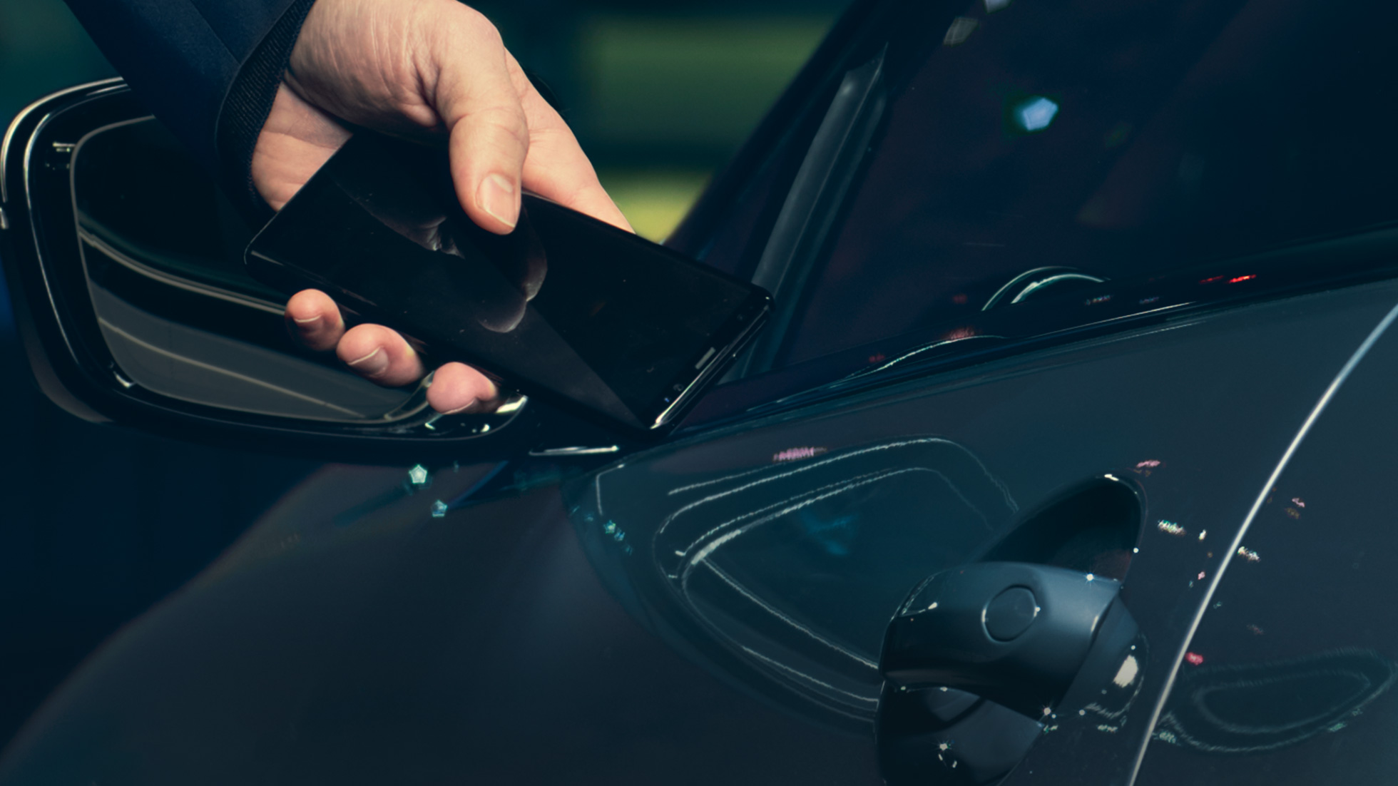 Digitalni ključ Digitalni ključ: Čovek drži svoj smartfon prema vratima vozila spolja
