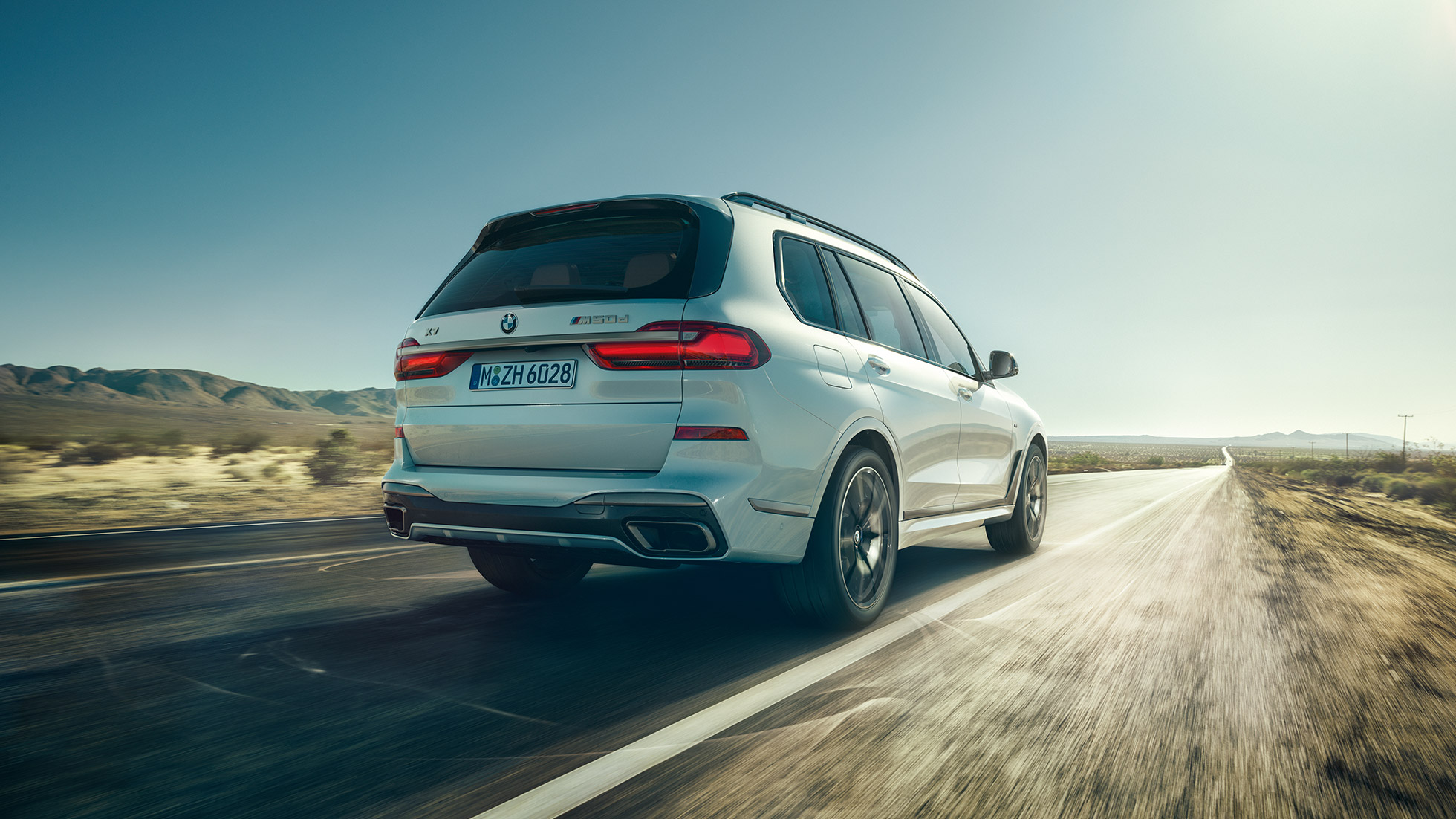 BMW X7 M50d, snimak otpozadi BMW X7 M50d: snimak otpozadi belog modela BMW X7 u vožnji