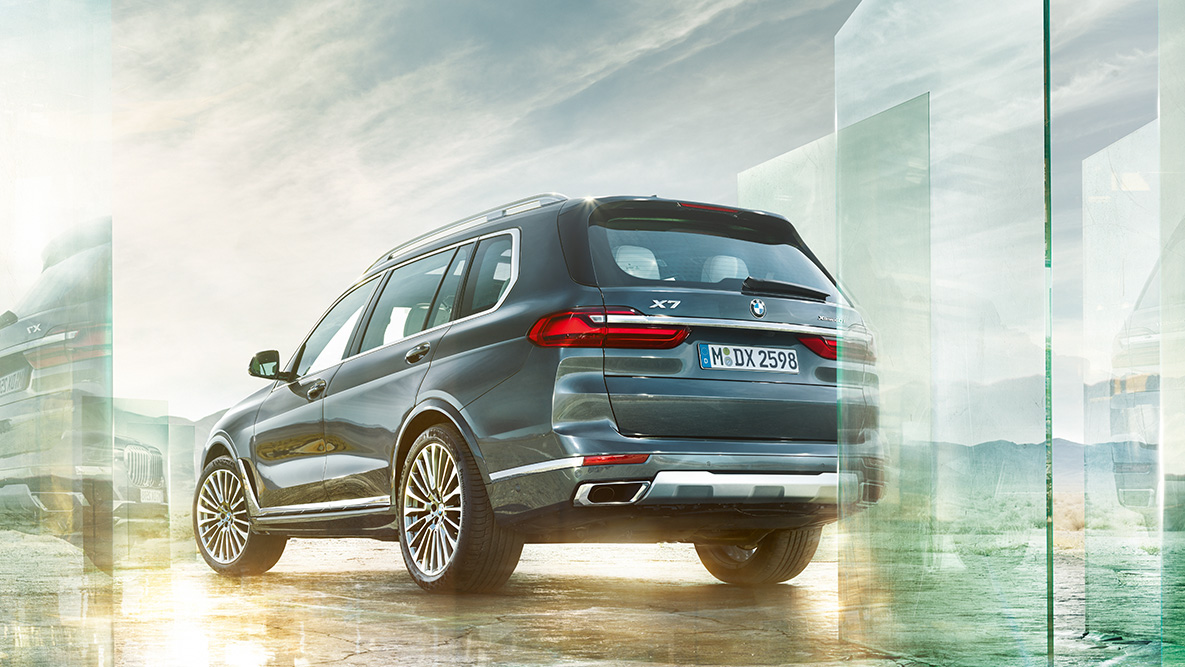 BMW X7 komfor i dinamičnost vožnje BMW X7 u tročetvrtinskom pogledu otpozadi ispred apstraktne pozadine