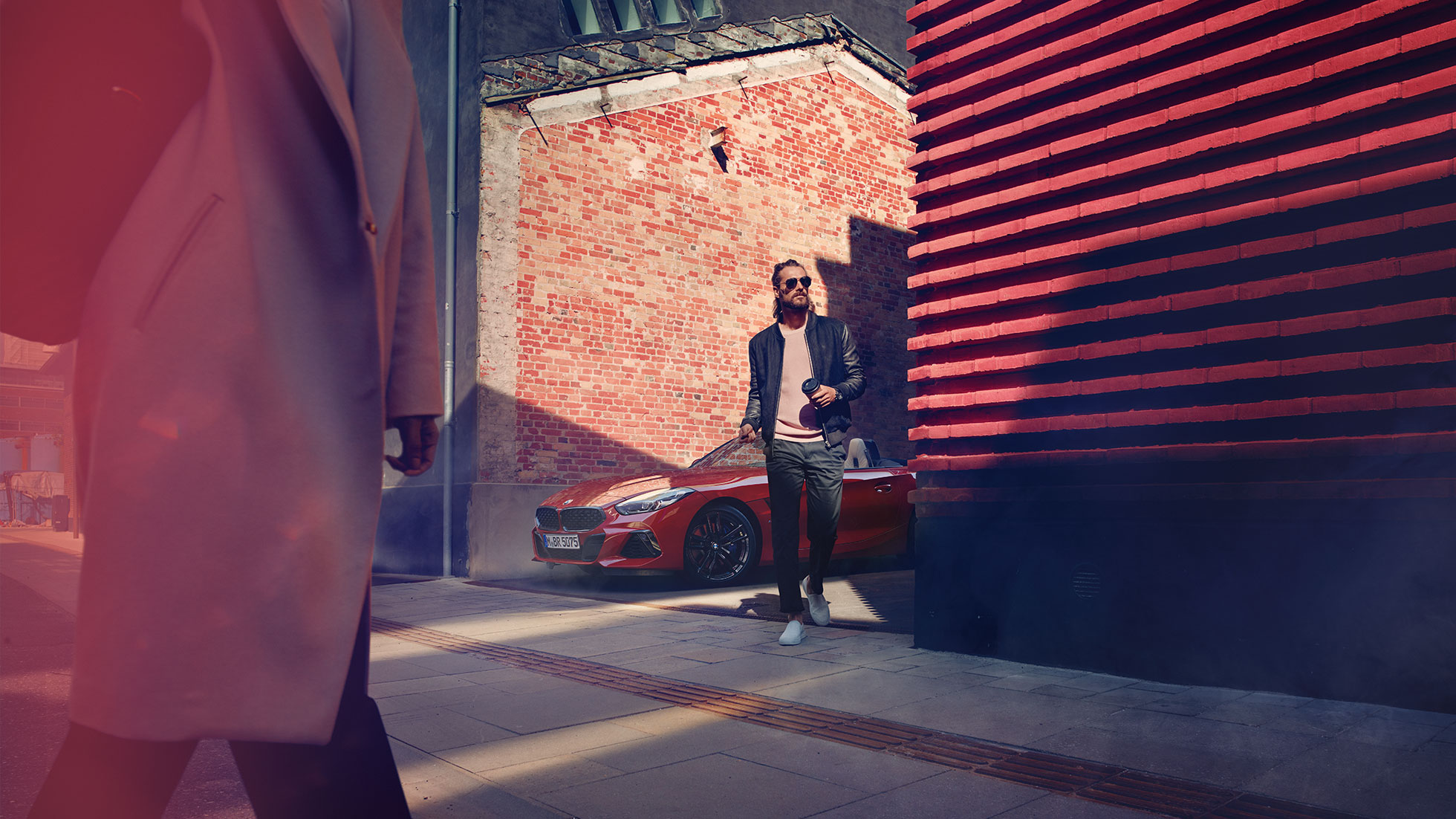 BMW Z4 Roadster u sporednoj ulici Muškarac u sporednoj ulici ispred modela BMW Z4 Roadster