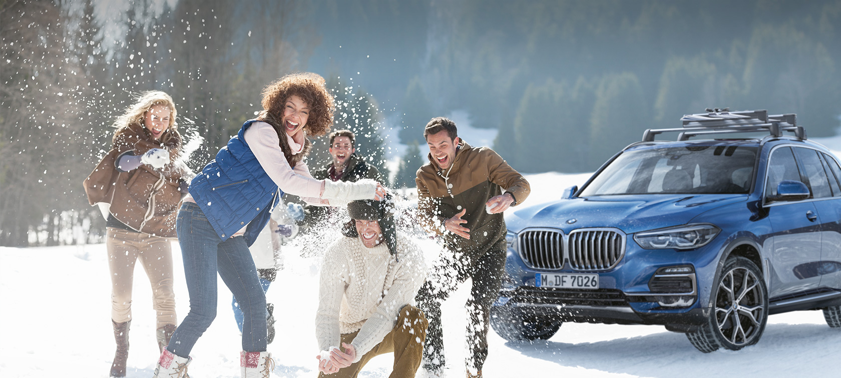 Originalni BMW dodaci i BMW servis za jesen i zimu Muškarac i žena ispred BMW-a u šumi