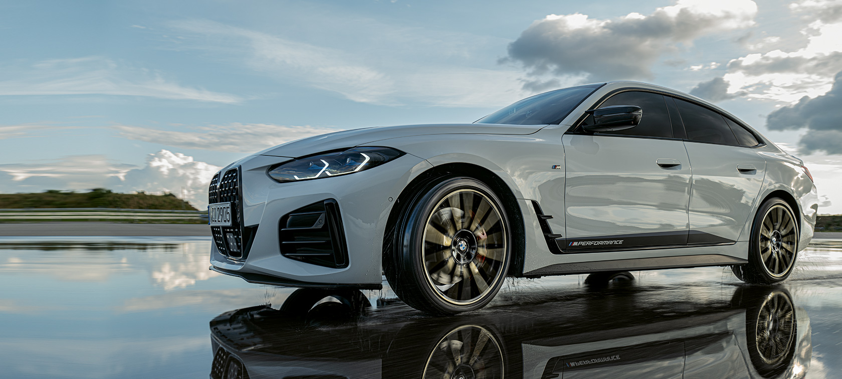 BMW Serija 4 Gran Coupé (G26) sa M Performance delovima u toku vožnje preko mokre ulice BMW Serija 4 Gran Coupé (G26) sa M Performance delovima u toku vožnje preko mokre ulice