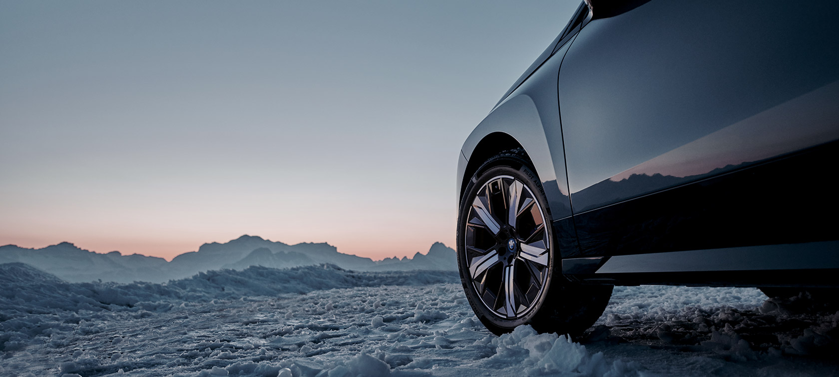 Originalni BMW točkovi na BMW iX (I20) na snegu isped planine Originalni BMW točkovi na BMW iX (I20) na snegu planine u pozadini